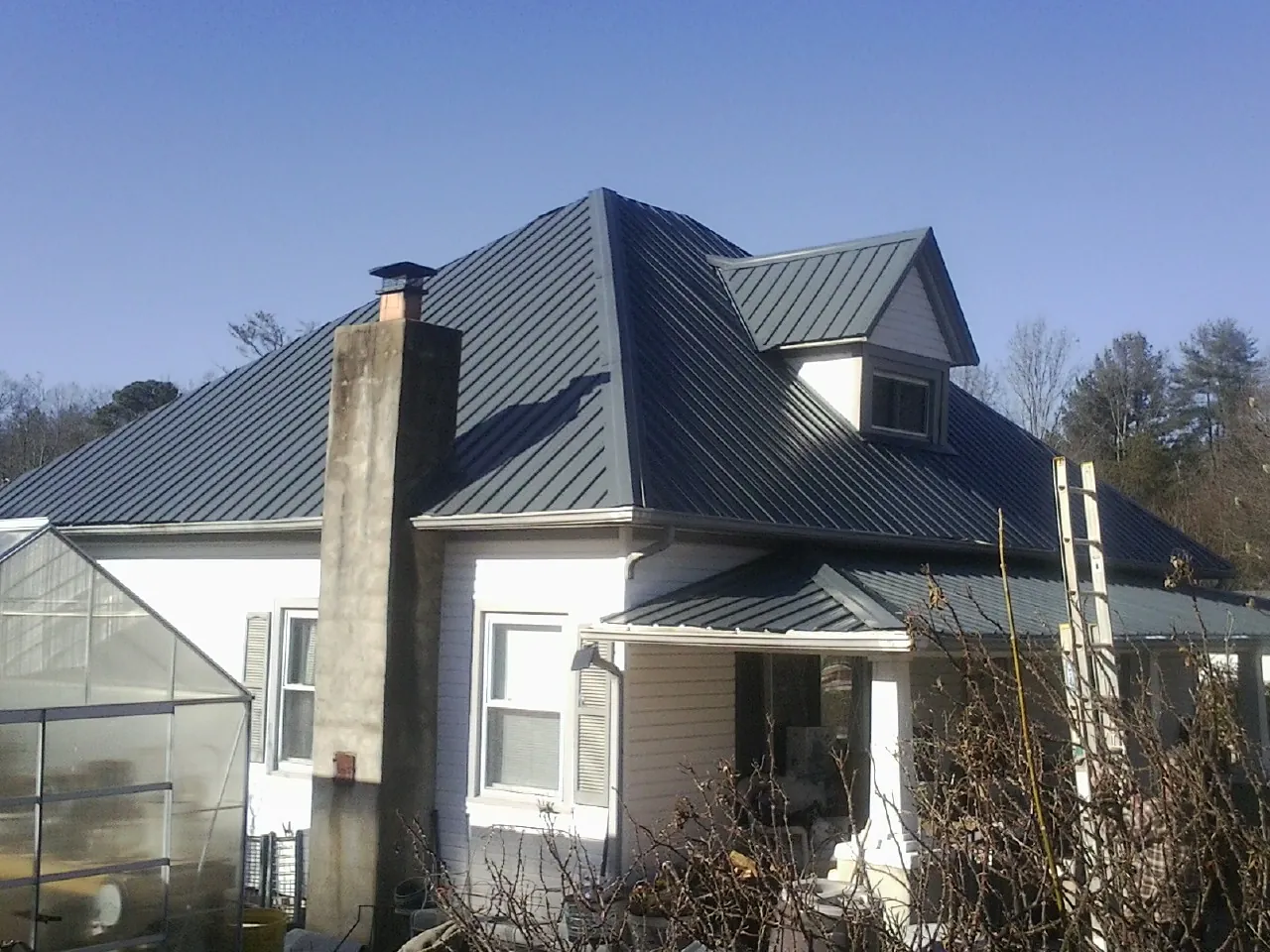 Dark blue standing seam metal roof on a white farmhouse with dormer — Slate & Tile Roof Repair by Roofing Brothers in Awendaw