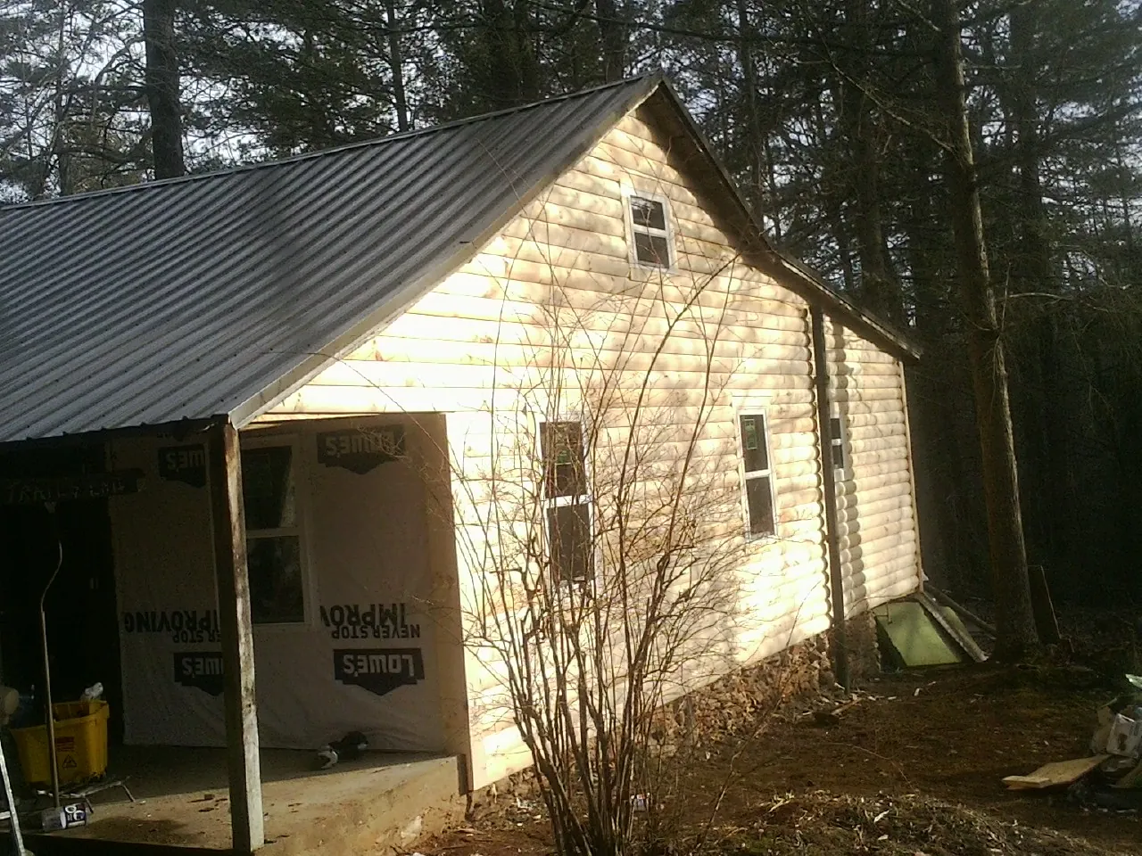 Log siding gable end under a dark metal roof edge in Awendaw