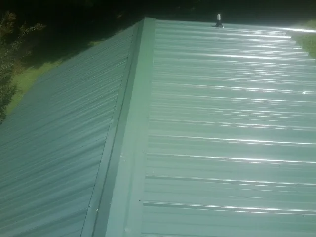 New green metal panels meeting at the ridge of a roof — Flat Roof Repair work by our crew in Awendaw
