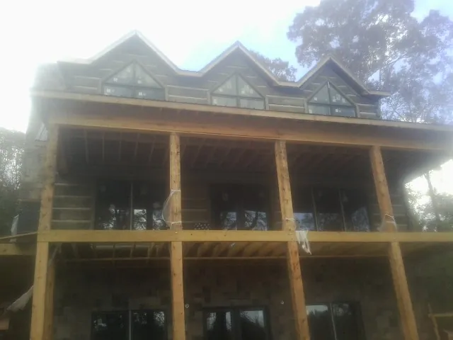 Dormers and porch framing on a large log home under construction — Roof Coating work by our crew in Awendaw