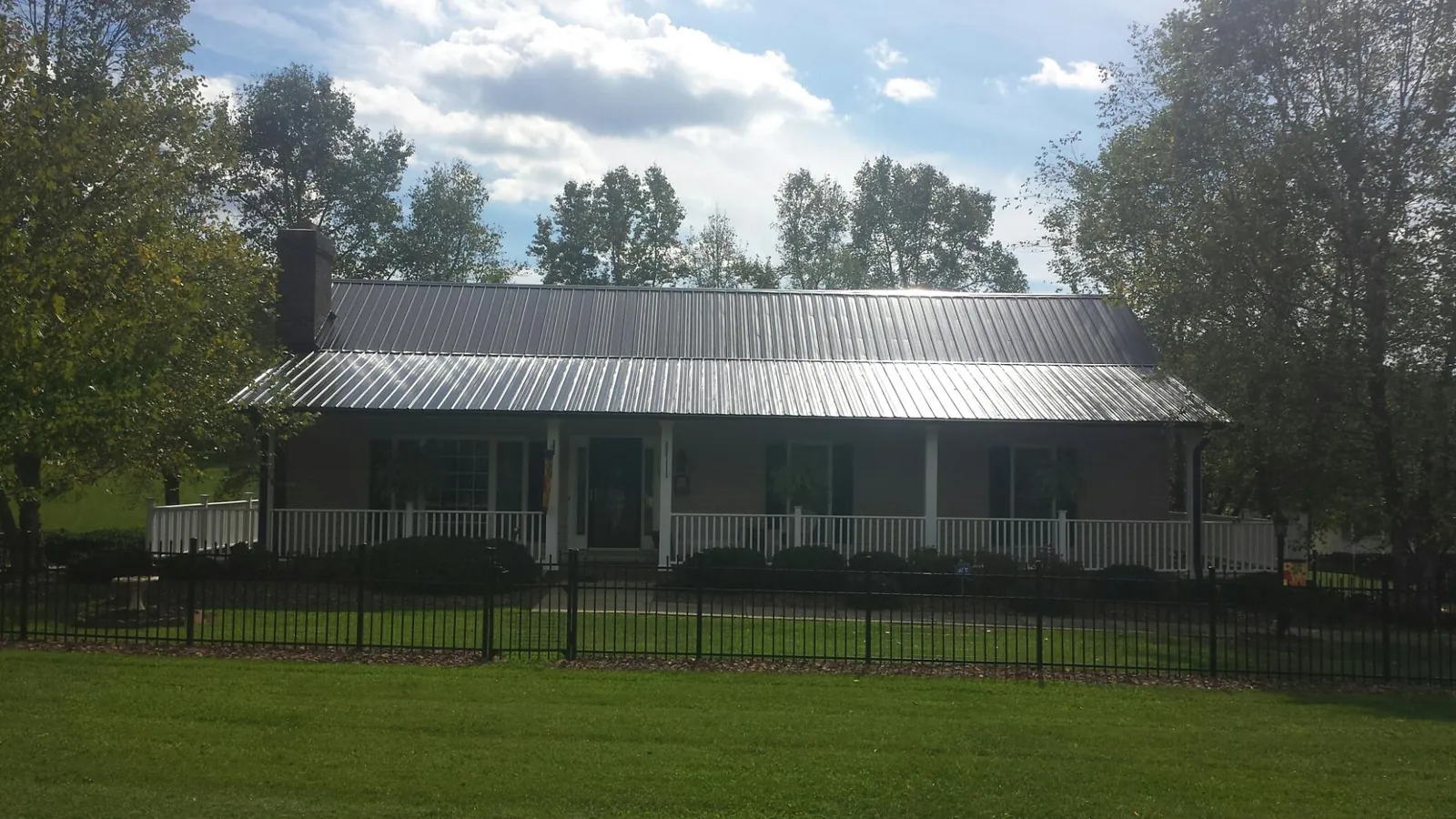 Gray metal roof on a brick ranch with a full width front porch — Gutter Guard Installation work by our crew in Awendaw