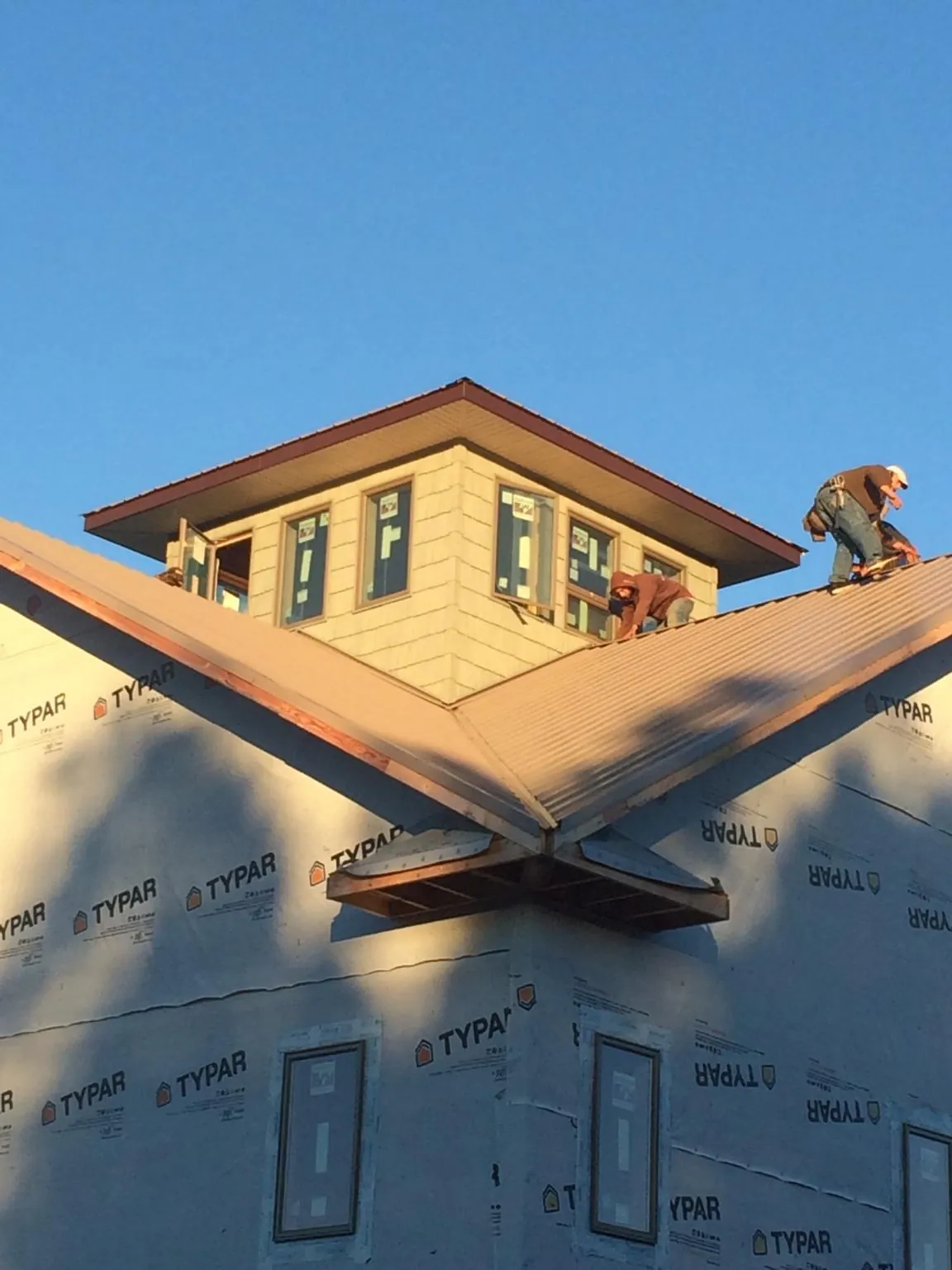 Roofers working around a rooftop cupola on a new metal roof at sunset — Roof Waterproofing in Awendaw by Roofing Brothers